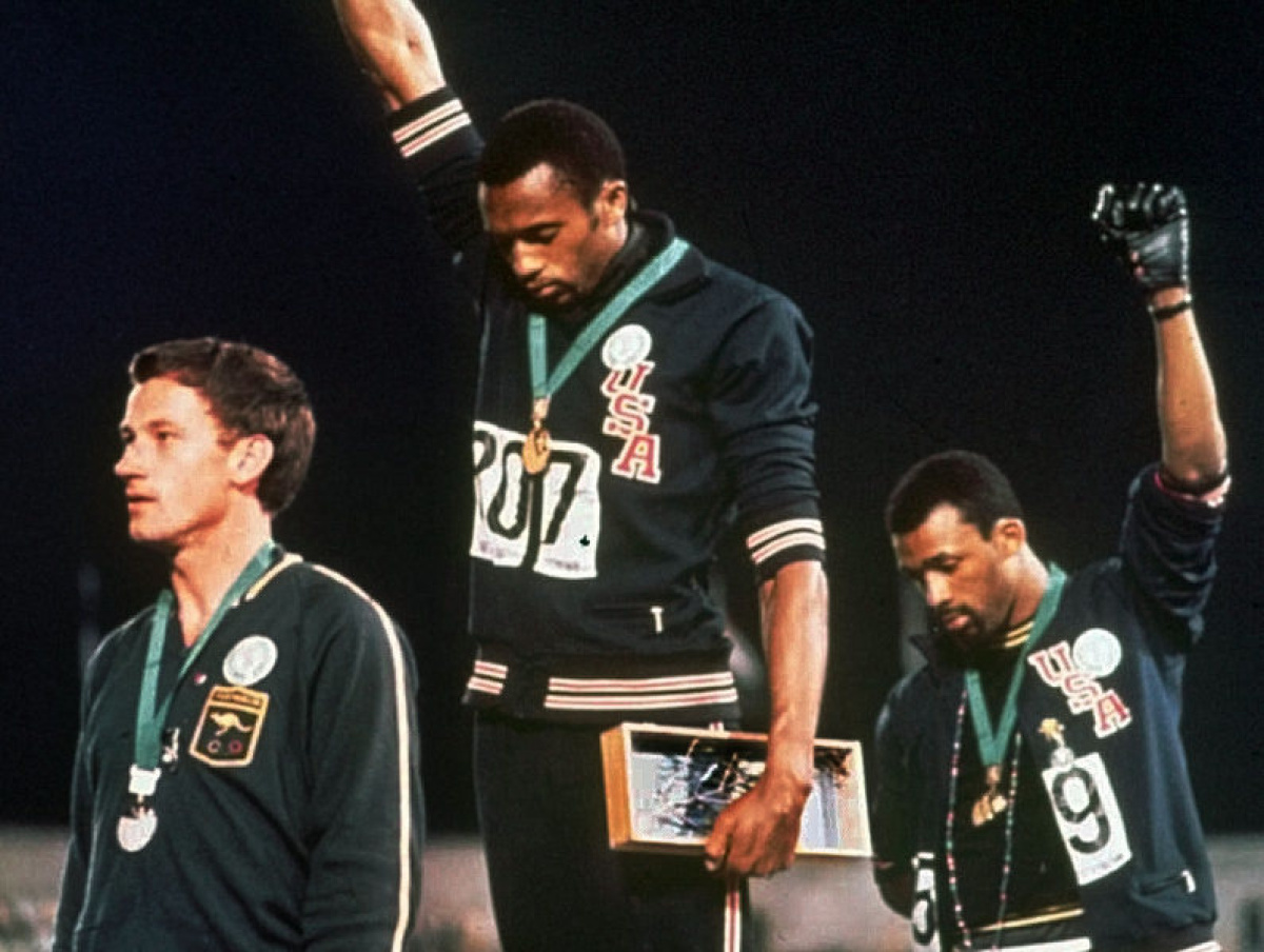 Extending gloved hands skyward in racial protest, U.S. athletes Tommie Smith, center, and John Carlos stare downward during the playing of the Star Spangled Banner after Smith received the gold and Carlos the bronze for the 200 meter run at the Summer Olympic Games in Mexico City on Oct. 16,__1968. Australian silver medalist Peter Norman is at left. (AP Photo)